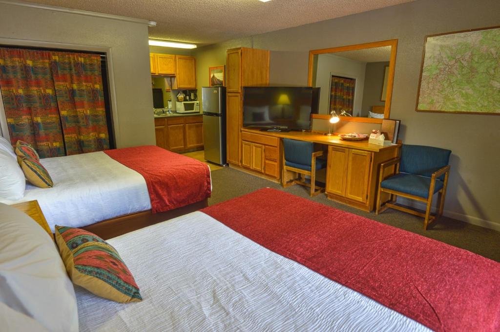 a hotel room with two beds and a desk and a television at Rustic Inn in Moab