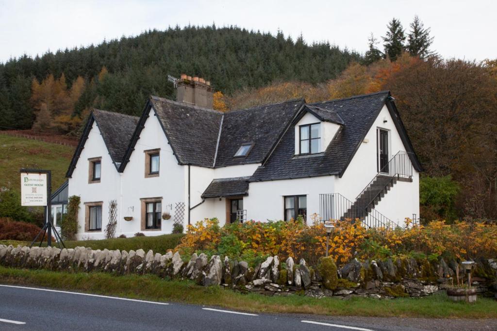 a white house with a black roof on the side of the road at Dunchraigaig House in Kilmartin