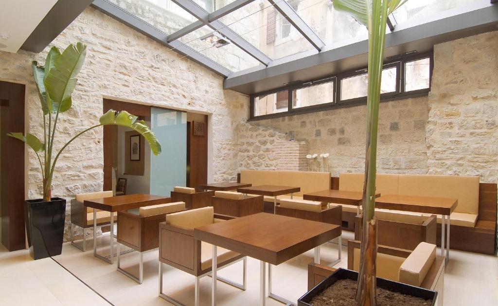 a dining room with tables and chairs and a plant at Hotel Vestibul Palace & Villa - Small Luxury Hotels Of The World in Split