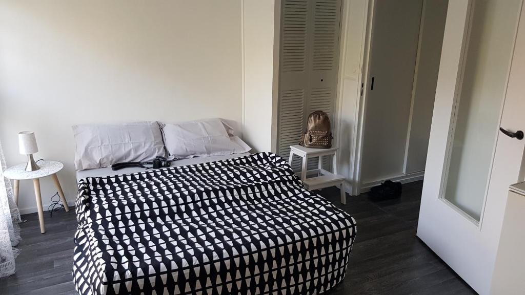 a bedroom with a black and white comforter on a bed at STUDIO en face de la forêt de FONTAINEBLEAU in Avon