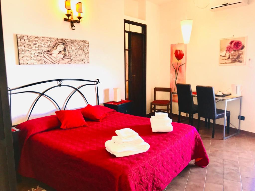 a bedroom with a red bed with two white towels on it at Villa Regina in Castelmola