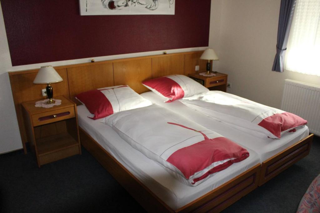 a large bed with red and white sheets and pillows at Landhaus Wilhelmshöhe in Uetze