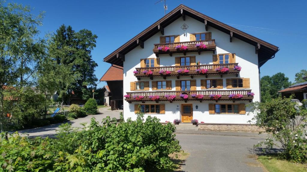 a white building with flowers on the balcony at Woidhauserhof in Waakirchen