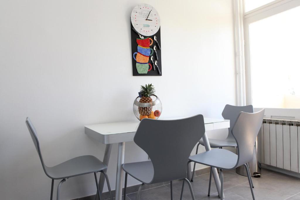 a dining room table with chairs and a clock on the wall at Résidence La Corvette in Toulon