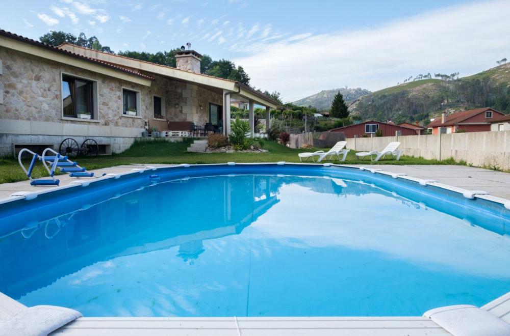 a large blue swimming pool in front of a house at Vila Compostela in Picoña