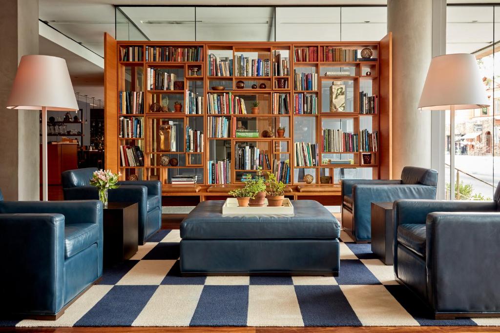 une bibliothèque avec des chaises bleues, une table et des étagères dans l'établissement The Study at Yale, Study Hotels, à New Haven