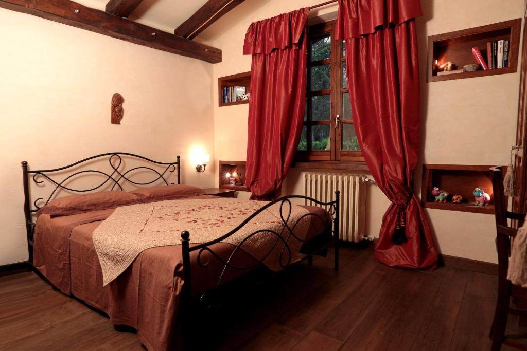 a bedroom with a bed with red curtains and a window at I Lari Castel Del Monte in Castel del Monte