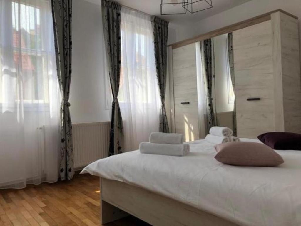 a bedroom with a large white bed with windows at CASA ALISE-LUISE in Braşov