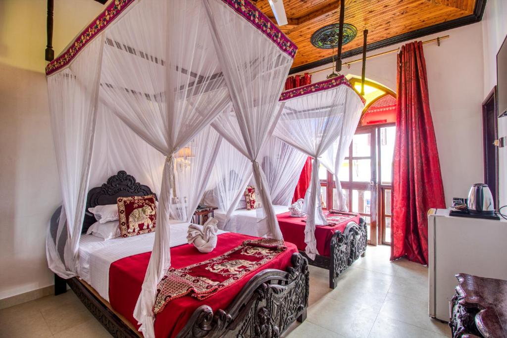 two beds in a room with mosquito nets at Tembo House Hotel in Zanzibar City