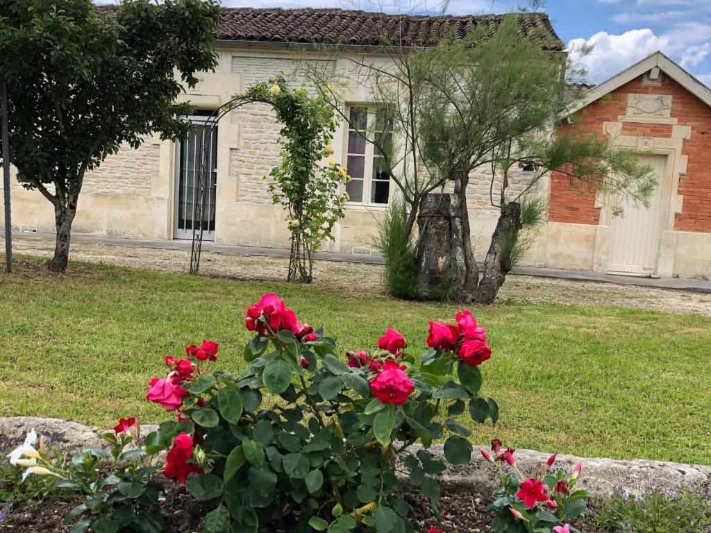 une maison avec des roses rouges devant une cour dans l'établissement Chez Lysette, à Mesnac