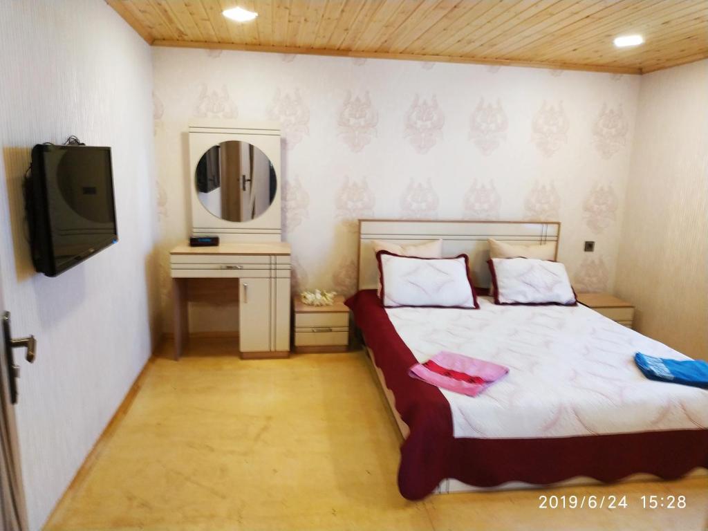 Schlafzimmer mit einem Bett mit einem Spiegel und einem TV in der Unterkunft Caspian Star in Sumqayıt