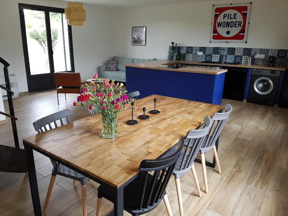 una mesa de madera con sillas y un jarrón de flores. en En plein maquis,entre mer&montagne en Vallecalle