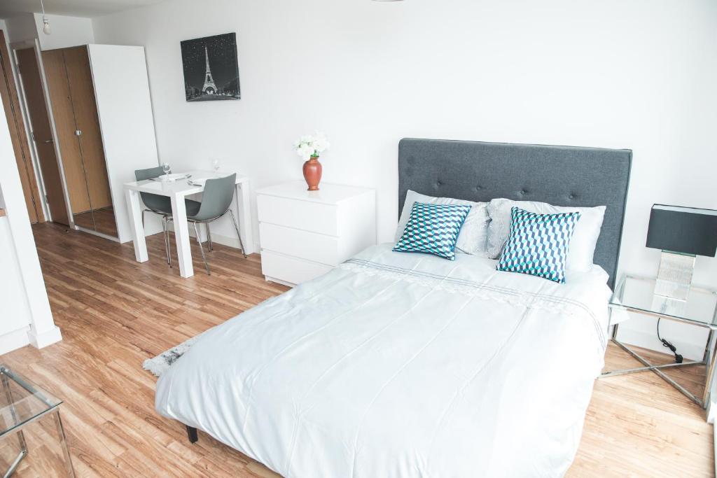 a bedroom with a large white bed with blue pillows at Studio Apartments Free street parking subject to availability in Manchester