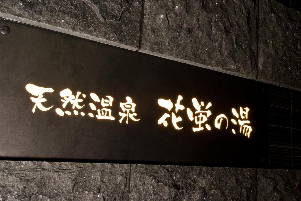 a sign on the side of a stone wall at Dormy Inn Premium Kyoto Ekimae Natural Hot Spring in Kyoto