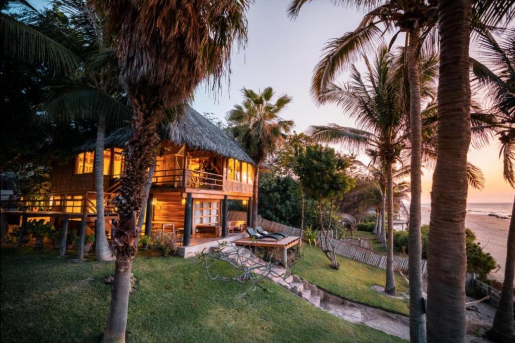 a house on the beach with palm trees at Coco Ne in Máncora