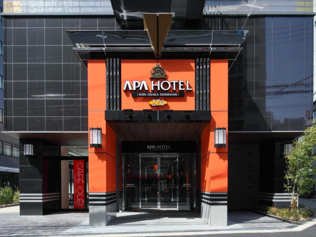 une entrée à un hôtel à la façade orange et noire dans l'établissement APA Hotel Shin-Osaka-Ekiminami, à Osaka