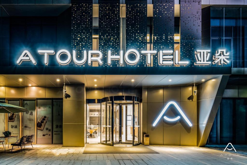 Atour Hotel Hangzhou Future Technology City Haichuang Park في هانغتشو: محل امام فندق اربعه بالليل