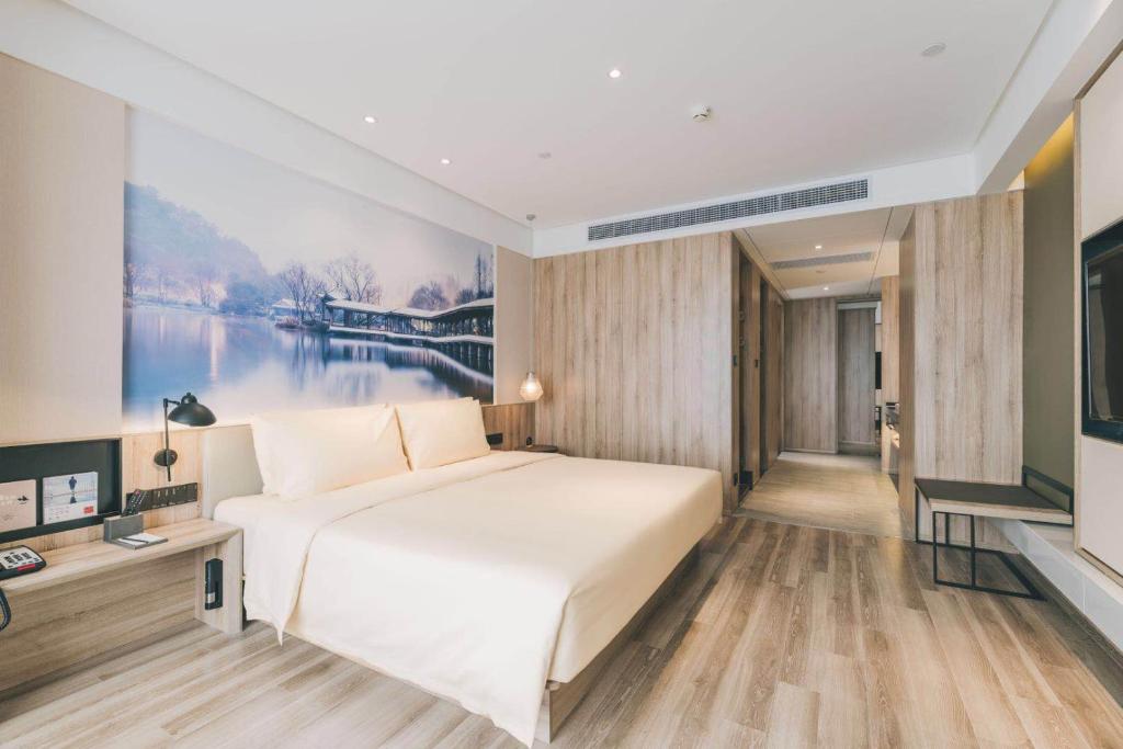 1 dormitorio con 1 cama blanca grande y TV en Atour Hotel Xiaoshan Airport Guali Branch, en Xiaoshan