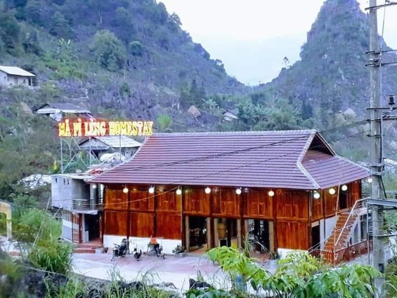 a building with a sign on the side of a mountain at Ma Pi Leng homestay in Làng Xao Vang