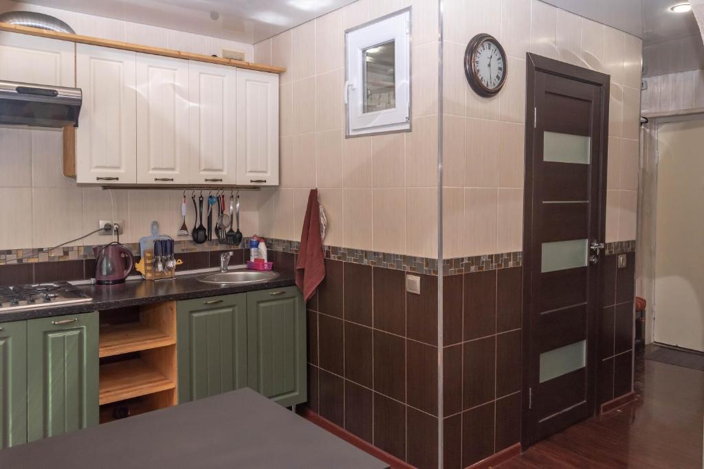 una cucina con armadi verdi e un orologio sul muro di Apartment on Fabrichnyi Pereulok 10 a Pereslavl-Zalesskiy