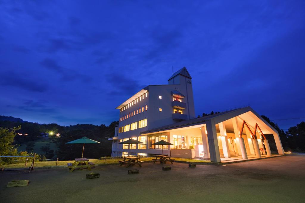 un grand bâtiment avec des tables devant lui la nuit dans l'établissement Asahi Shizenkan, à Asahi-machi