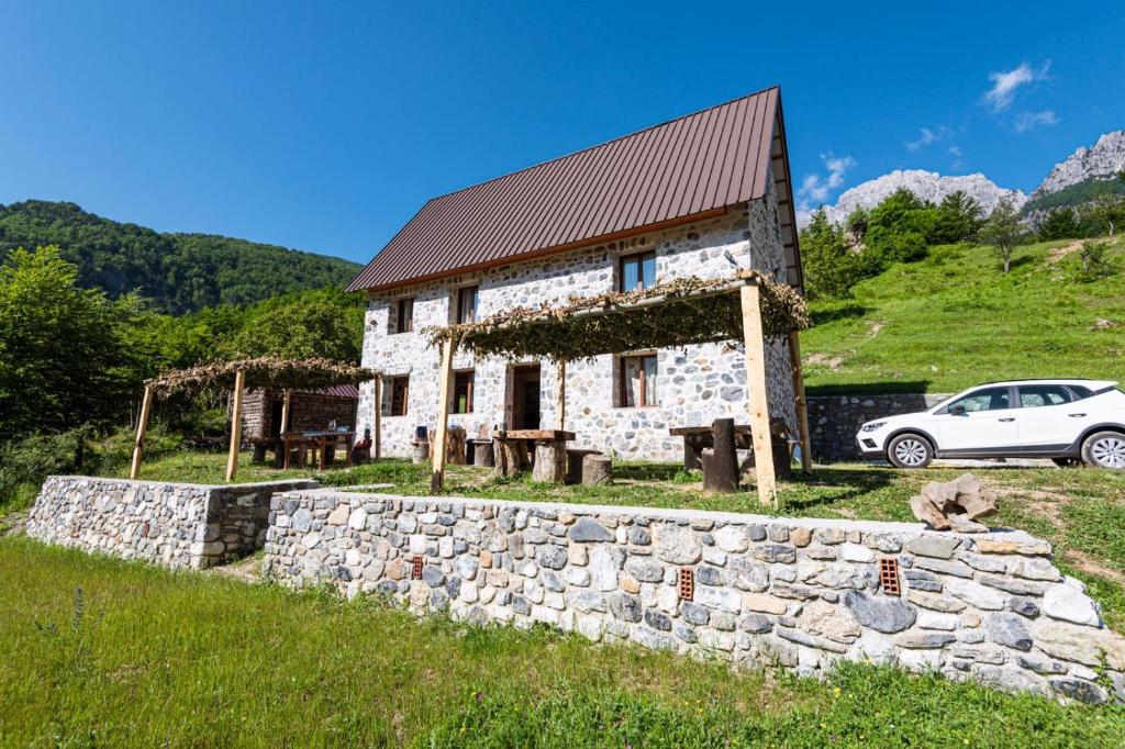 una casa in pietra con un'auto parcheggiata di fronte di Guest house PANORAMA a Theth