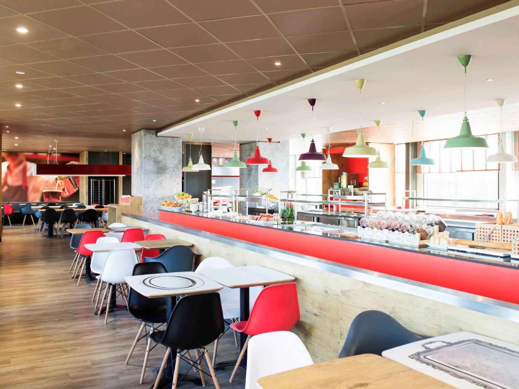 a restaurant with tables and chairs and a counter at Ibis Schiphol Amsterdam Airport in Badhoevedorp