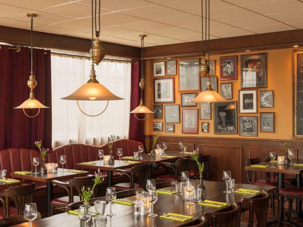 a restaurant with tables and chairs and pictures on the walls at Ibis Schiphol Amsterdam Airport in Badhoevedorp