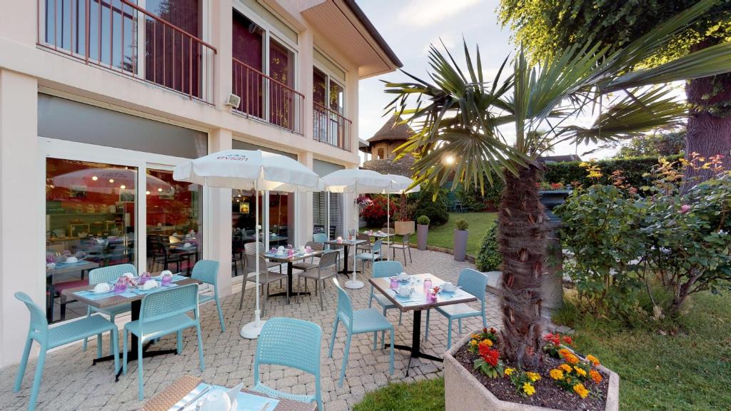 a restaurant with tables and chairs and a palm tree at Hôtel de France Contact-Hôtel in Évian-les-Bains