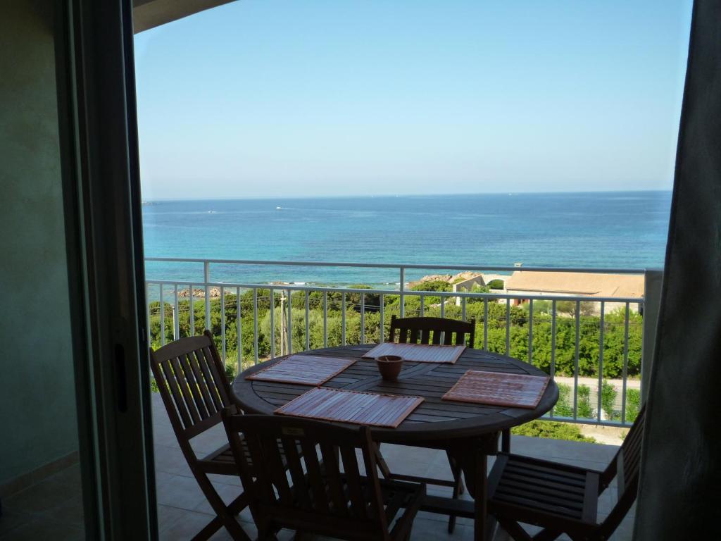 uma mesa e cadeiras numa varanda com o oceano em APPARTEMENT PIED DANS L EAU ET VUE MER MAGNIFIQUE em Sartène