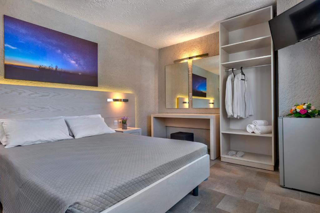 a bedroom with a white bed and a fireplace at Halaris Rooms in Ermoupoli