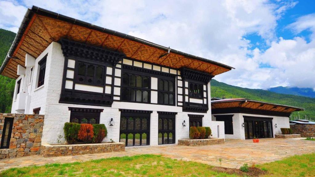een groot wit huis met een bruin dak bij The Village Lodge Bumthang in Bumtang Tang
