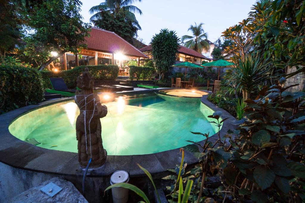a swimming pool with a fountain in a yard at Argasoka Bungalows in Ubud
