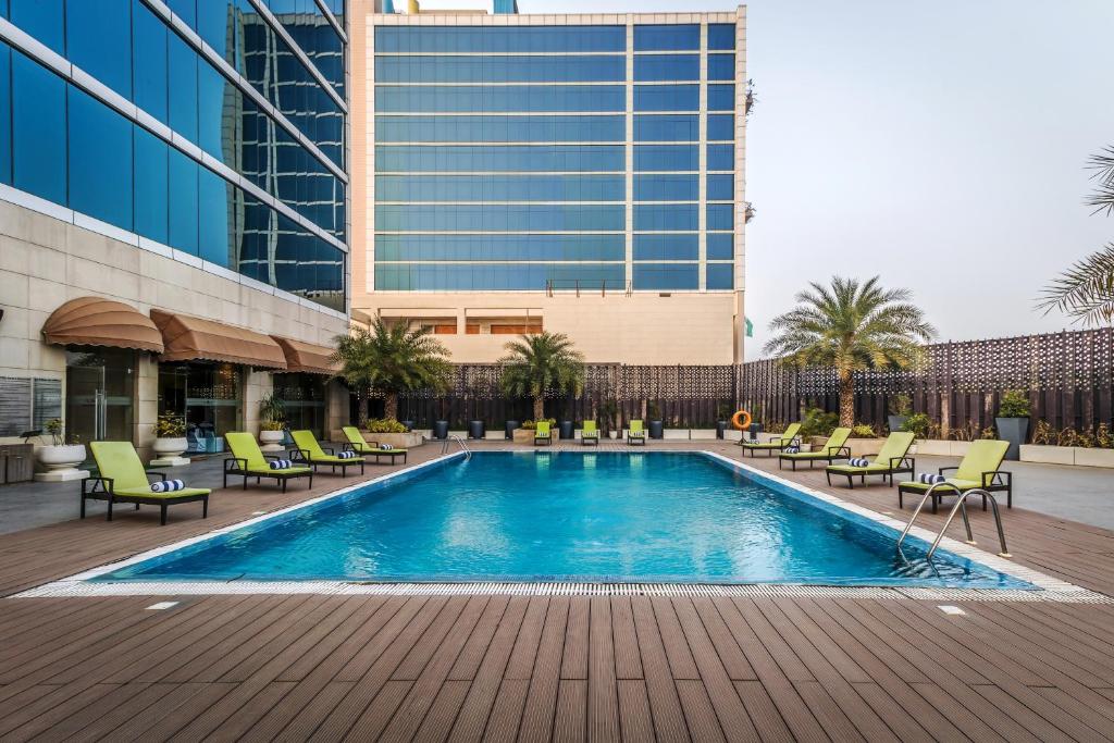 a swimming pool with chairs and a building at Golden Suites Gurugram by Inde Hotels in Gurgaon