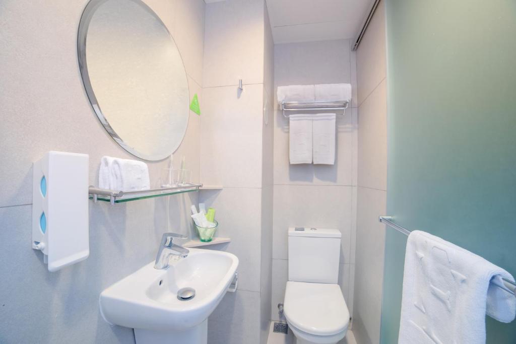 a bathroom with a sink and a toilet and a mirror at Hotel Ease Mong Kok in Hong Kong