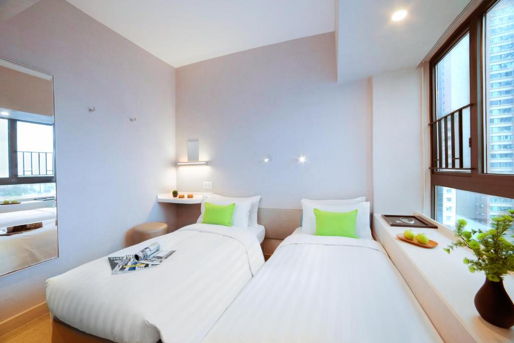 two beds in a room with two windows at Hotel Ease Mong Kok in Hong Kong