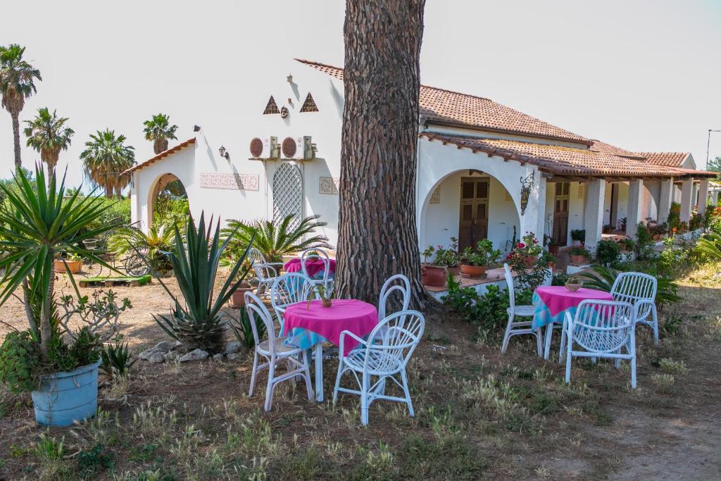 a group of pink tables and chairs around a tree at Residenza il Normanno - La terrazza sul mare in Santa Domenica