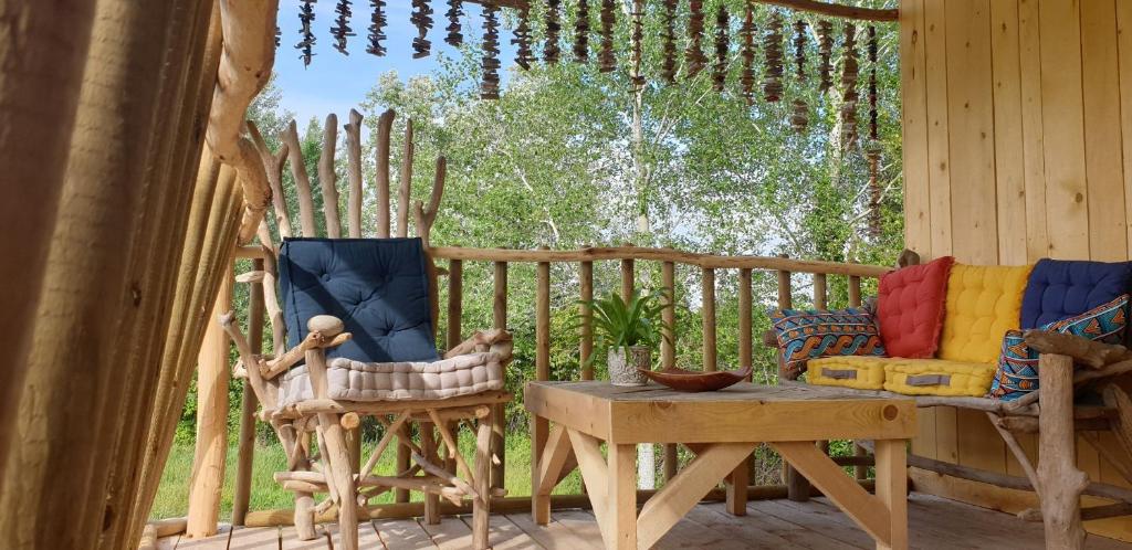 a porch with two chairs and a table and a fence at LA CABANE PERCHEE in Villelaure