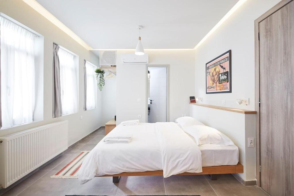 1 dormitorio blanco con 1 cama grande y ventanas en Stay in a hip decorated studio near Acropolis!, en Atenas