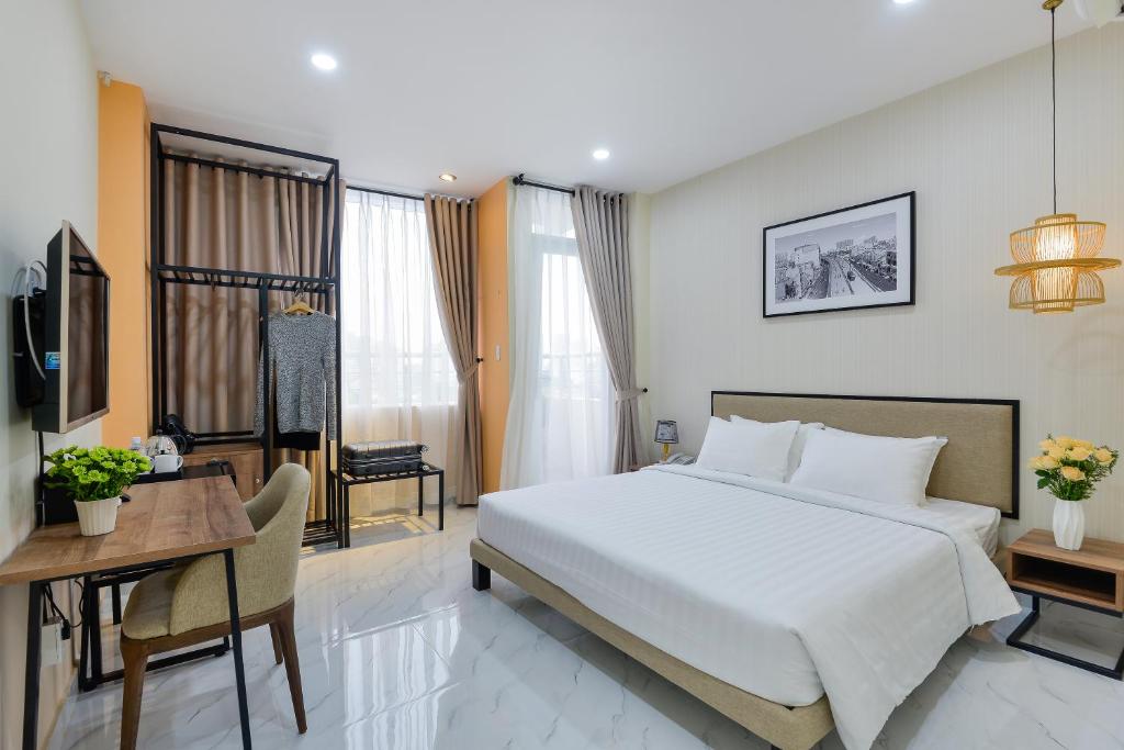Pokój hotelowy z łóżkiem, stołem i biurkiem w obiekcie The Akoya Saigon Hotel w Ho Chi Minh