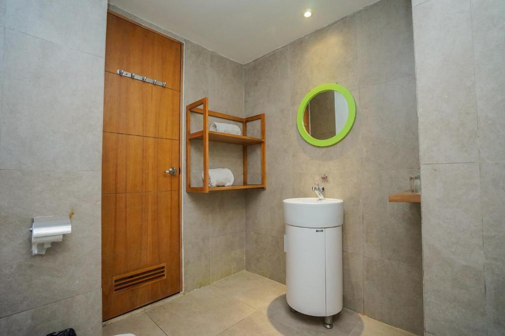 a bathroom with a toilet and a green mirror at Radja Art and Boutique Hotel Simpang Lima in Semarang