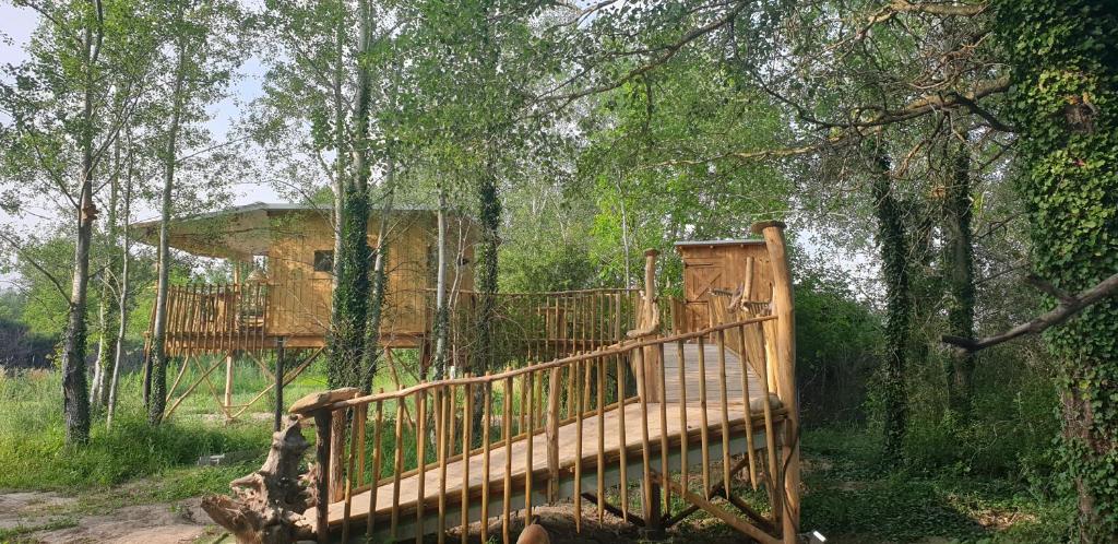 a tree house with a deck in the woods at LA CABANE PERCHEE in Villelaure