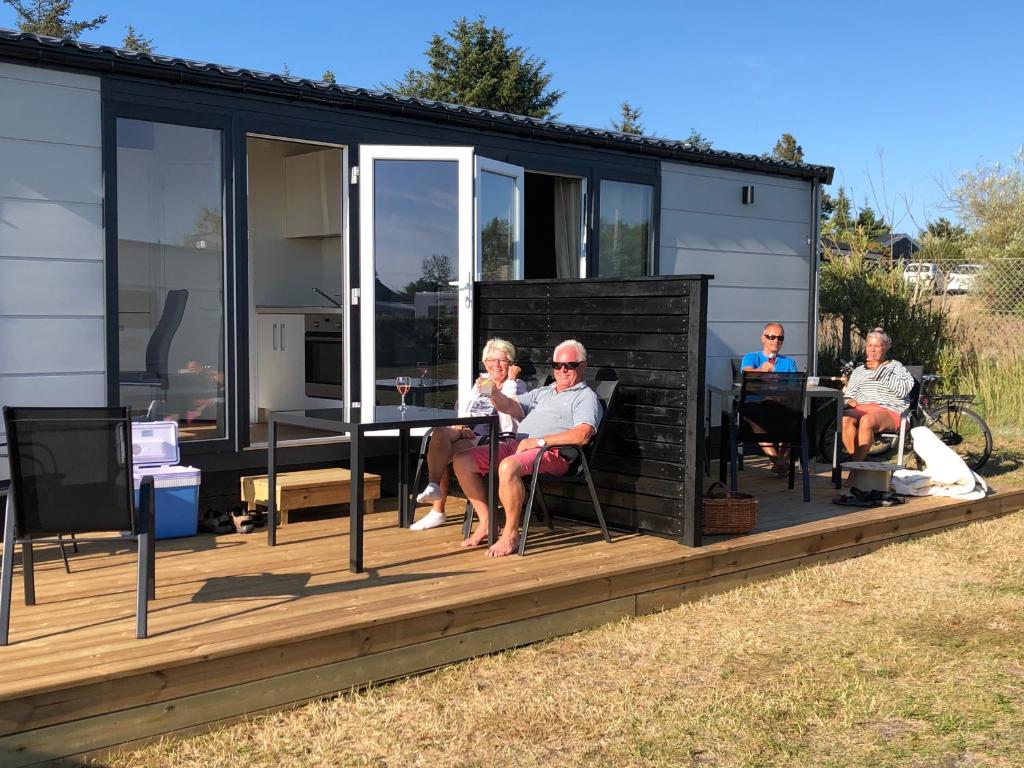 Un groupe de personnes assises sur le pont d'une petite maison dans l'établissement Tannisby Camping, à Tversted