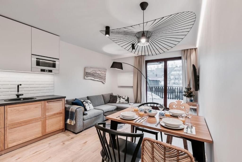 uma cozinha e sala de estar com uma mesa e um sofá em Apartament Wierchy em Zakopane
