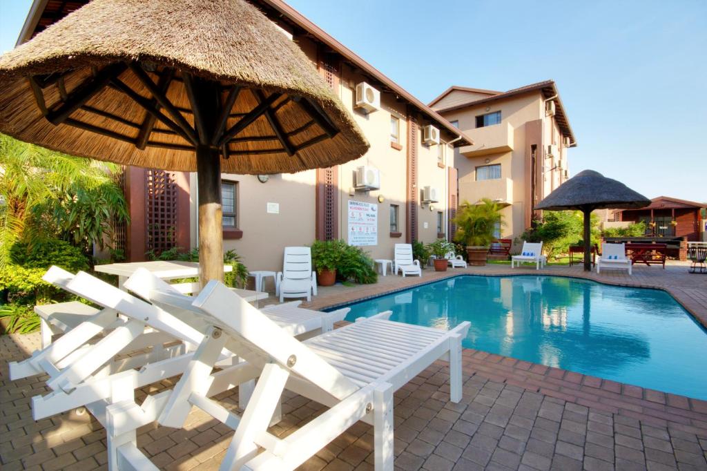 a group of chairs and an umbrella and a pool at Seagull Lodge in Richards Bay