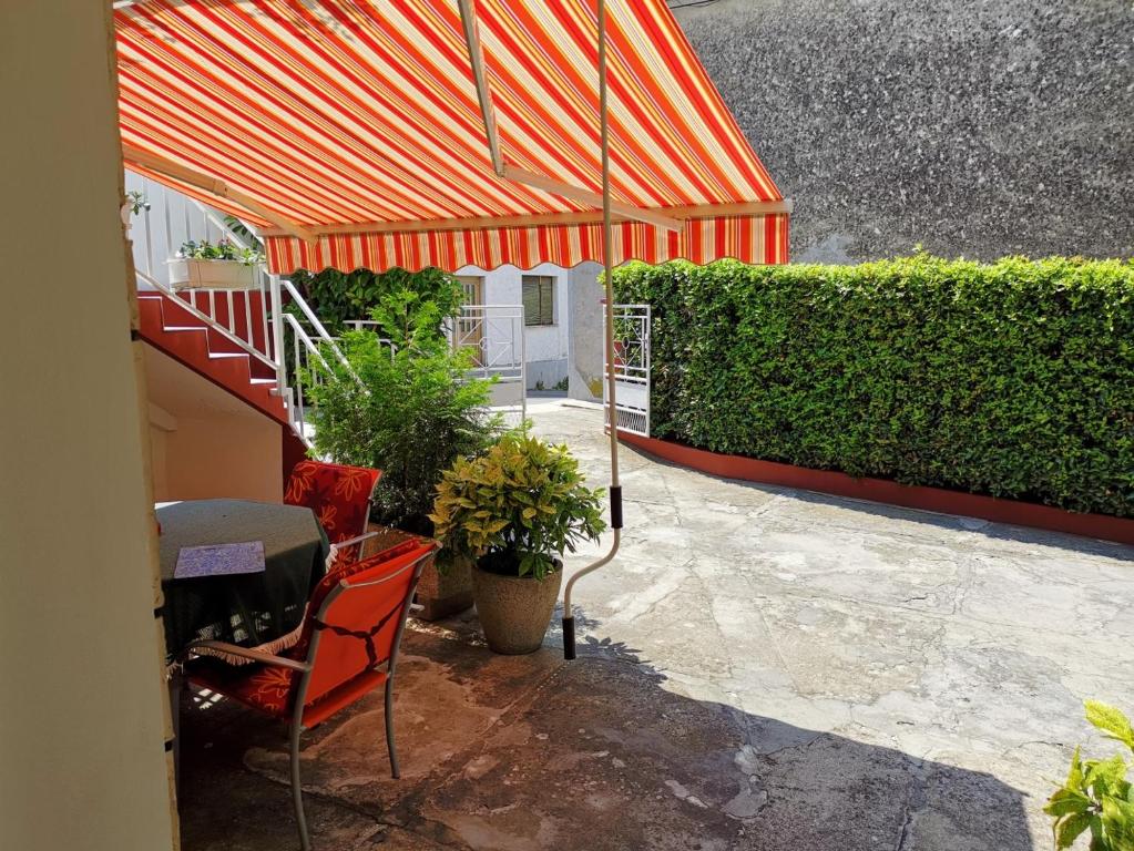 a patio with an orange umbrella and a chair and plants at Apartment Dino in Novi Vinodolski