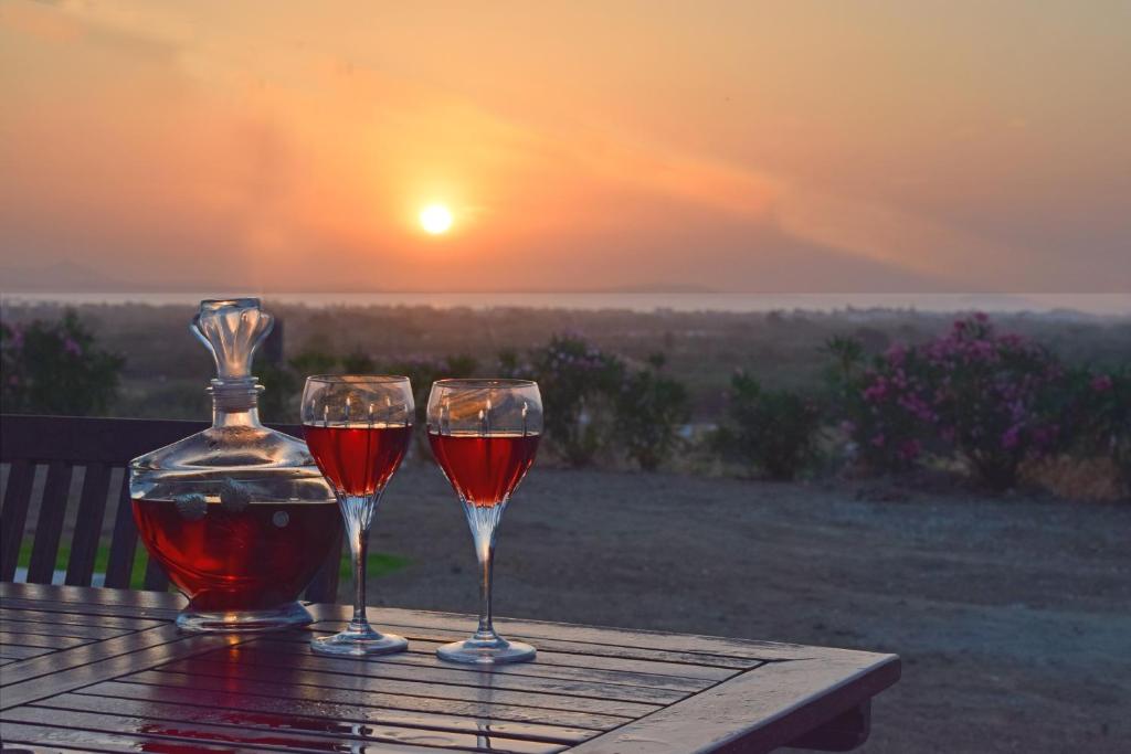 Naxian vacation with sea view في ناكسوس تشورا: كأسين من النبيذ يجلسون على طاولة مع غروب الشمس
