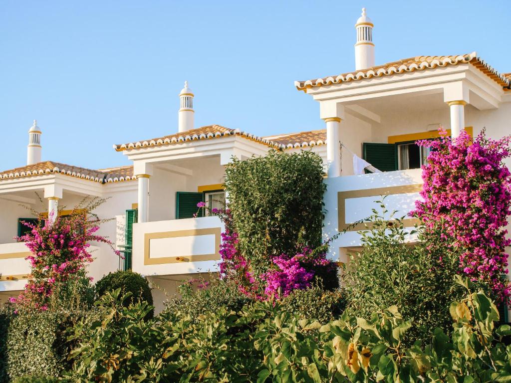 a white house with pink flowers in front of it at Vale d'El Rei Hotel & Villas in Carvoeiro