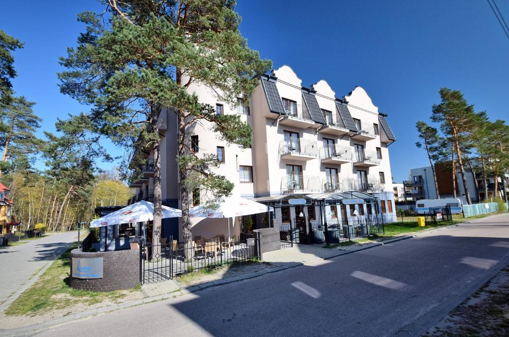 a building with a tree in front of a street at Lazur Wellness@Spa in Międzywodzie