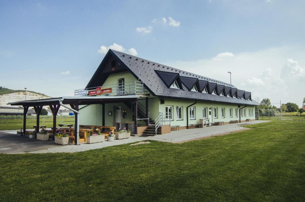 ein Gebäude mit einem schwarzen Dach und einem Grasfeld in der Unterkunft Guest House Na Hřišti in Leština